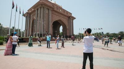 Tourists take photos in front of Emirates Palace. Mona Al Marzooqi / The National