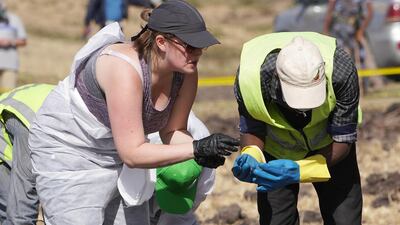 Forensic investigators and recovery teams collect personal belongings and other material from the crash site. Getty Images