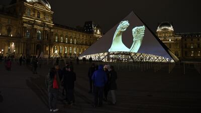 Images of the art displayed in the Louvre Abu Dhabi are projected onto the Louvre Pyramid in Paris Wednesday night to mark the opening of the museum on Saadiyat island. Eric Feferberg / AFP