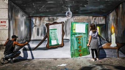 Palestinian-Syrian artist Ghayath al-Roubeh (L) and Lebanese artist Nagham Abboud paint a mural depicting a 100,000 Lebanese pound banknote being reflected in a mirror as a 1000 Lebanese pound note, symbolising the level of inflation caused by the shrinking Lebanese economy, at al-Nour Square in Lebanon's northern port city of Tripoli, July 8. AFP