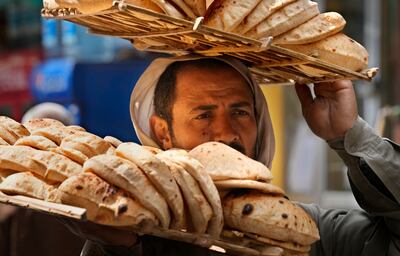 A bread seller carries a tray of Egypt's traditional 'baladi' flatbread outside a bakery, in Cairo. AP
