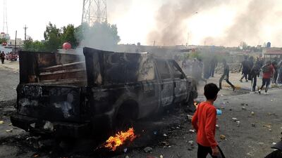 Iraqi protesters gather as smoke rises from a burning military truck after clashes between protesters and Iraqi policemen in Nasiriyah city, some 370km southeast of Baghdad, Iraq. EPA