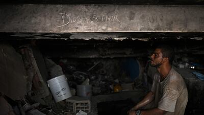 A volunteer searching for the bodies of earthquake victims takes a rest under a beam of a collapsed building where "God is love" has been written in the dust, in Caraballeda, La Guaira state, Venezuela. AFP