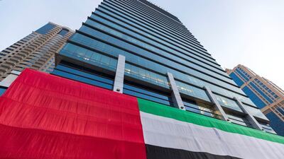 A giant flag is displayed on a skyscraper in JLT for the National Day. Chris Whiteoak / The National