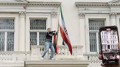A protester pulls down the Iranian flag from the balcony of Iran's embassy in central London on Saturday. AFP