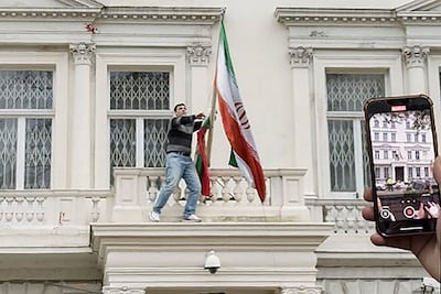 A protester pulls down the Iranian flag from the balcony of Iran's embassy in central London. AFP