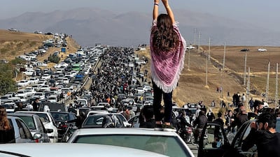 A woman stands on top of a vehicle as thousands protest in western Iran, defying heightened security measures. AFP