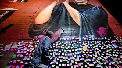Andrew Oros looks at messages of thanks and gratitude taped on a mural memorial to Ginsburg in Washington. AFP