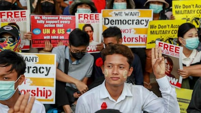 Anti-coup protesters flash the three-fingered salute of resistance and display pictures of deposed Myanmar leader Aung San Suu Kyi in Yangon, Myanmar on February 25, 2021. AP