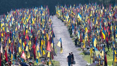 People walk among graves at the Field of Mars cemetery in Lviv to commemorate the fallen soldiers on the occasion of the Independence Day of Ukraine. AFP