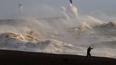 A person takes photographs of the sea as waves crash against the breakwater in Newhaven. AFP