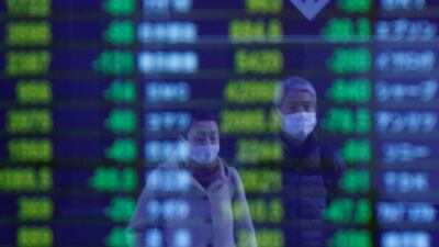 Pedestrians walk outside a brokerage in Tokyo on Friday. Declines in major US indices Thursday were followed by drops in Asia in morning trading. Reuters