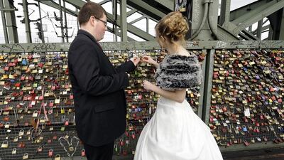 Newlyweds Alicia of Wisconsin, right, and Sven from Cologne fix a padlock to a fence on a train bridge over the Rhine in Cologne, Germany. The custom says that lovers will cement their love with the lock when they throw the key into the river. Martin Meissner / AP