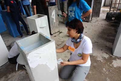 Noora Almulla, Soroptimist International Dubai president, helps build a toilet for the community in the Davao region of the Philippines.