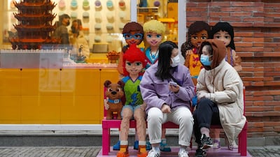 Women wearing protective masks to prevent the new coronavirus outbreak chat with each other outside a Lego store at a re-opened commercial street in Wuhan in central China's Hubei province. AP