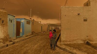 A father carries his daughter as rain clouds gather in Kabul. April 19, 2015. Shah Marai / AFP