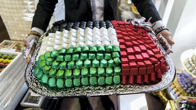 Abdulaziz Diag, Morrocan, 29, shows the UAE flag-themed chocolate options available at the store he manages, Chocolate Boutique. Reem Mohammed / The National