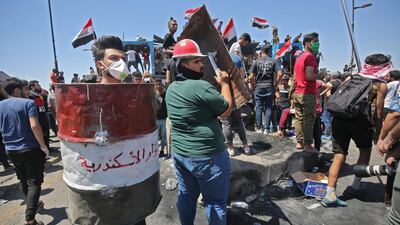 An Iraqi protester uses half a barrel as a shield during an anti-government demonstration on Al-Jumhuriyah bridge in the capital Baghdad. AFP