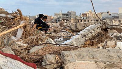 People sit among the rubble in Derna.