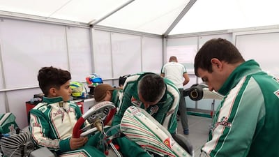 A young Rashid Al Dhaheri sits on his Tony Kart Racing Team kart as mechanics work on it. Handout image