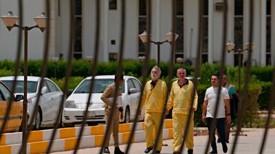 Jim Fitton, center left, and Volker Waldmann, center right, are handcuffed as they walk outside a courtroom in Baghdad, Iraq. AP.