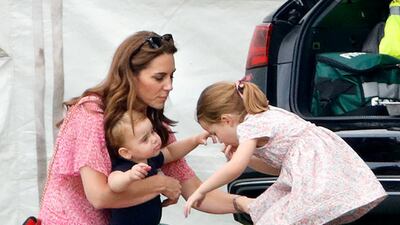 Catherine, Duchess of Cambridge, holds Prince Louis while Princess Charlotte plays during the King Power Royal Charity Polo Match at Billingbear Polo Club in Wokingham in July 2019. Getty Images