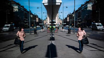 A woman wearing a protective face mask checks her reflection on a window in Stockholm, Sweden, on April 2, 2020. AFP