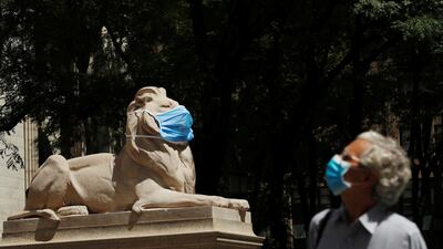 A large mask hangs on the face of a lion statue standing outside of the main branch of the New York Public Library in the Manhattan borough of New York City, US. Reuters