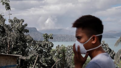 A man wears a mask as the Taal volcano continues to spew smoke and ash in Tanuan, Batangas, Philippines. EPA