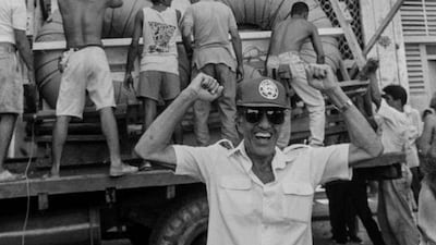 A man gestures as a makeshift boat is lowered from a roof where it was built.