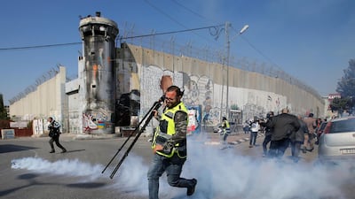 A Palestinian journalist runs away from tear gas fired by Israeli forces during a protest in Bethlehem obver the shooting of Muath Amarneh. Reuters