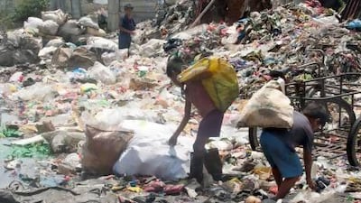 Scavengers push a cart loaded with reclaimed wood through the muddy roadway of a squatter's village at Smokey Mountain, a landfill in Manila so named because of the toxic fumes that billow from the site. Mike Young for The National