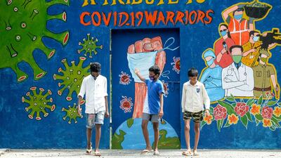 A youth gestures as he walks with others past a mural dedicated to frontline workers in Chennai. AFP