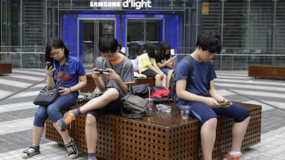 Middle school students use their smartphones in front of a Samsung showroom in Seoul, South Korea. AP Photo