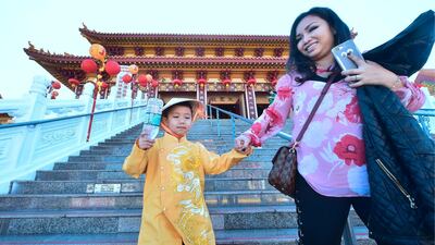 Dressed in imperial costume, Bruce Q Tran holds onto his mother Nhi's hands while they walk down steps at the Hsi Lai (Come West) Buddhist Temple in Hacienda Heights, California on the eve of the Lunar New Year. Frederic J Brown / AFP Photo