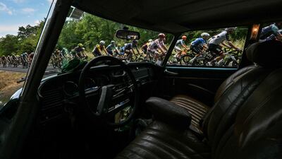Tour de France riders pass a classic car during stage 12 of the race, between Circuit de Nevers Magny-Cours and Chalon-sur-Saone in central France. AFP