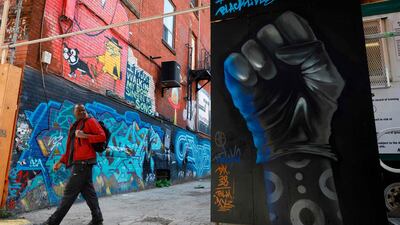 A man walks past a gloved fist painted on a wall at Graffiti Alley in Toronto, Ontario, Canada. AFP