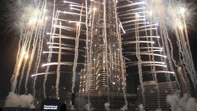Crowds look at fireworks bursting around Burj Khalifa, the tallest building in the world, marking the New Year at midnight on January 1, 2011 in the Gulf emirate of Dubai. AFP PHOTO