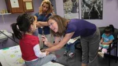 Jessica Mejia looks on as her daughter, Joselyn, is examined by Kim Gracey, a physician's assistant at the Rocky Mountain Youth Clinic.