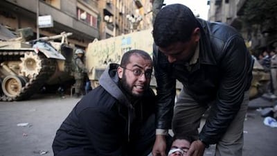 An injured anti-government protester is administered first aid in front of army vehicles during clashes in Tahrir Square in Cairo. Human rights workers suggest the army is quite capable of cracking down when it wants.