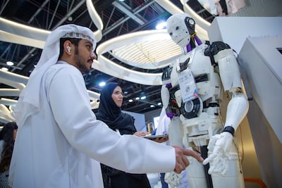 A man interacting with a robot inside Abu Dhabi Government stand at Gitex. Leslie Pableo / The National
