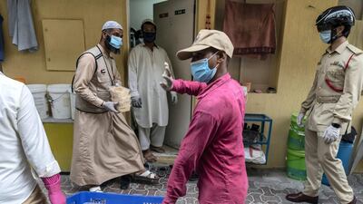 Dar Al Ber Iftar meals are handed out as part of their charity work at labour camps in Al Qouz 1. Keeping a watchfull eye is Dubai Police officers from the Bur Dubai Police Station monitoring body temperature with the new thermal helmet camera. Antonie Robertson/The National