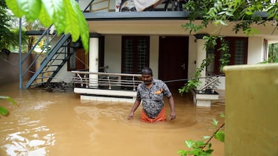 A man walks in a flooded street outside a house in Kochi, Kerala. EPA