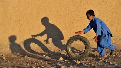 An Afghan child plays with a tire along a street in a village on the outskirts of Jalalabad. Noorullah Shirzada / AFP