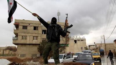 A Syrian soldier, who has defected to join the Free Syrian Army, holds up his rifle and waves a Syrian independence flag in the Damascus suburb of Saqba today.