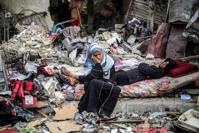 People sit amid ruins in central Gaza. AFP