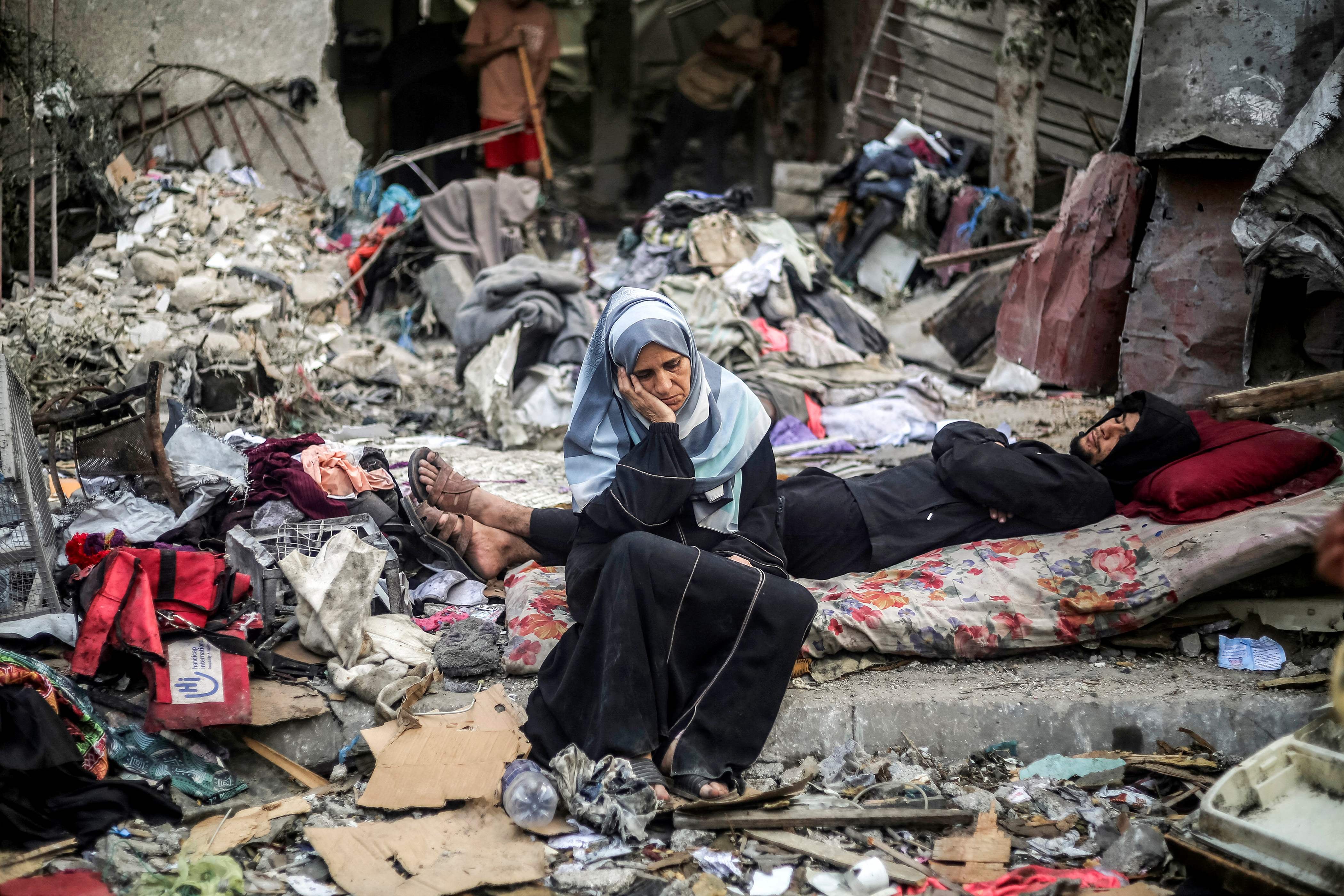 People sit amid ruins in central Gaza. AFP