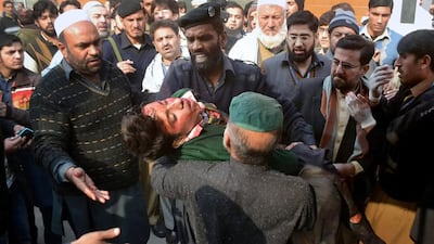 An injured schoolboy is carried to hospital by security guards after the attack by Taliban gunmen on an army high school in Peshawar. Mohammad Sajjad / AP Photo