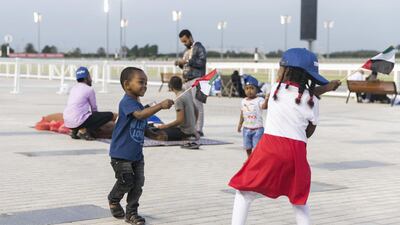 A boy and a girl carry the UAE flag at Meydan. Reem Mohammed / The National