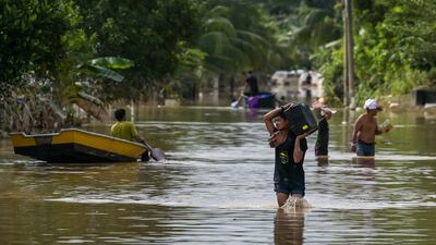 Residents walk along a road submerged by floodwaters in Mentakab in Malaysia's Pahang state following heavy rains that have displaced hundreds of thousands of people. AFP